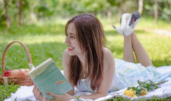 A woman enjoys a sunny day reading at a picnic in Ho Chi Minh City, surrounded by nature.